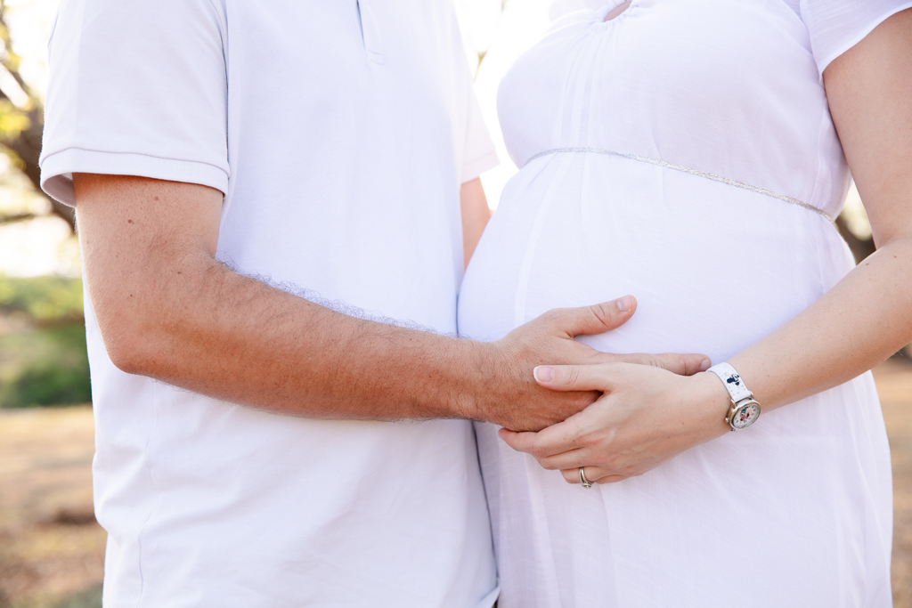 Close-up maternity photo of pregnant belly with partner’s hands in Nelspruit