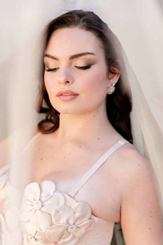 Bride wearing romantic wedding makeup featuring glowing skin, neutral eye makeup, and long lashes.